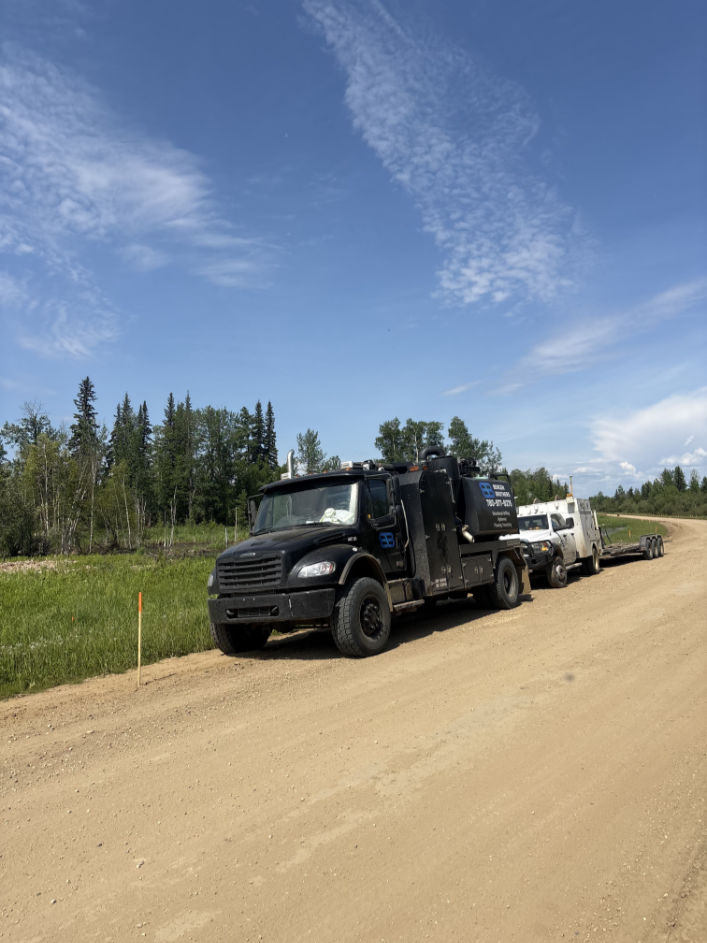 Bergen Brothers Daylighting hydrovac truck working on a rural Alberta daylighting site with trees, equipment, and off-road access.