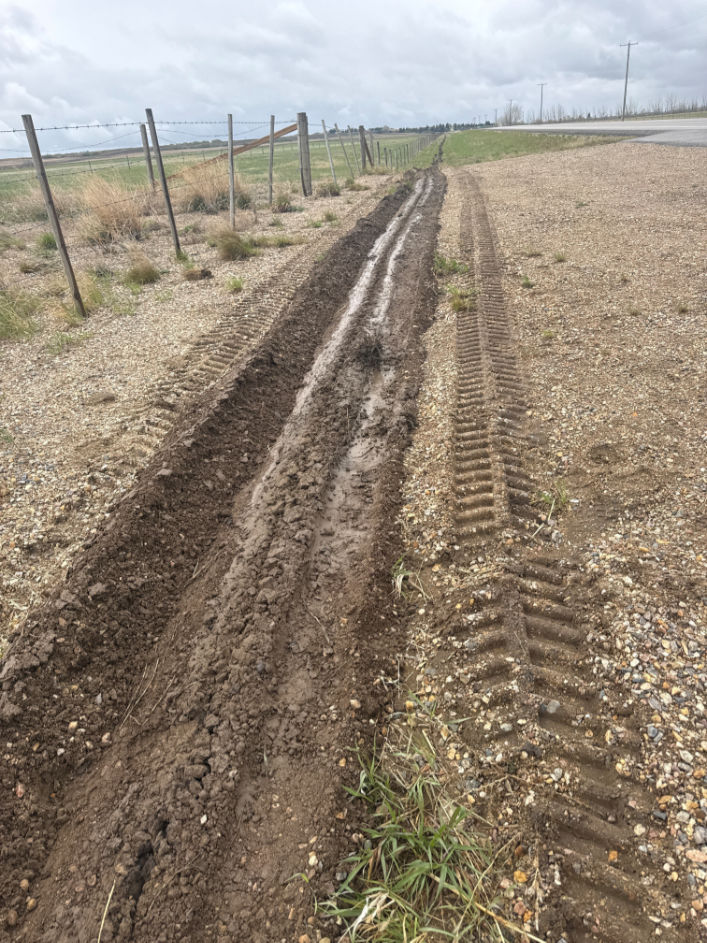 Roadside utility plowing by Bergen Brothers Daylighting for underground line installation near a gravel access road.